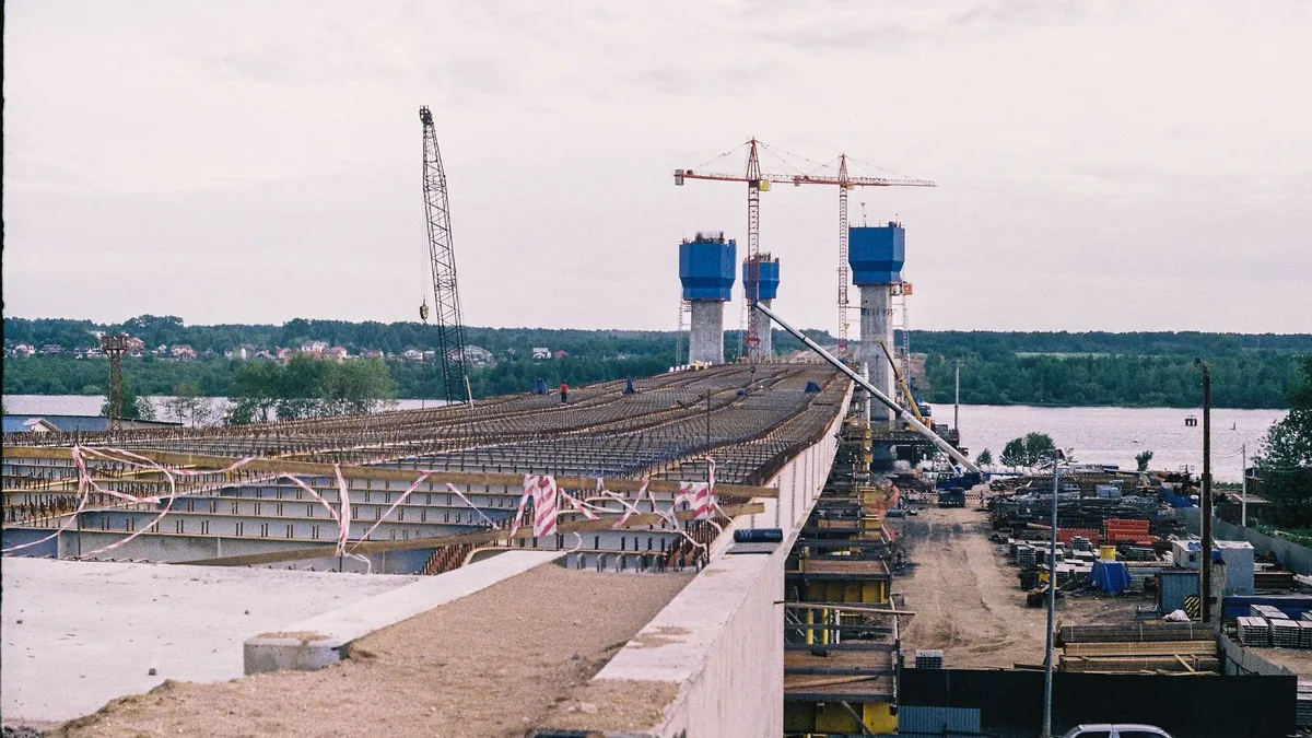 Grande cantiere infrastrutturale con viadotto in costruzione e gru
